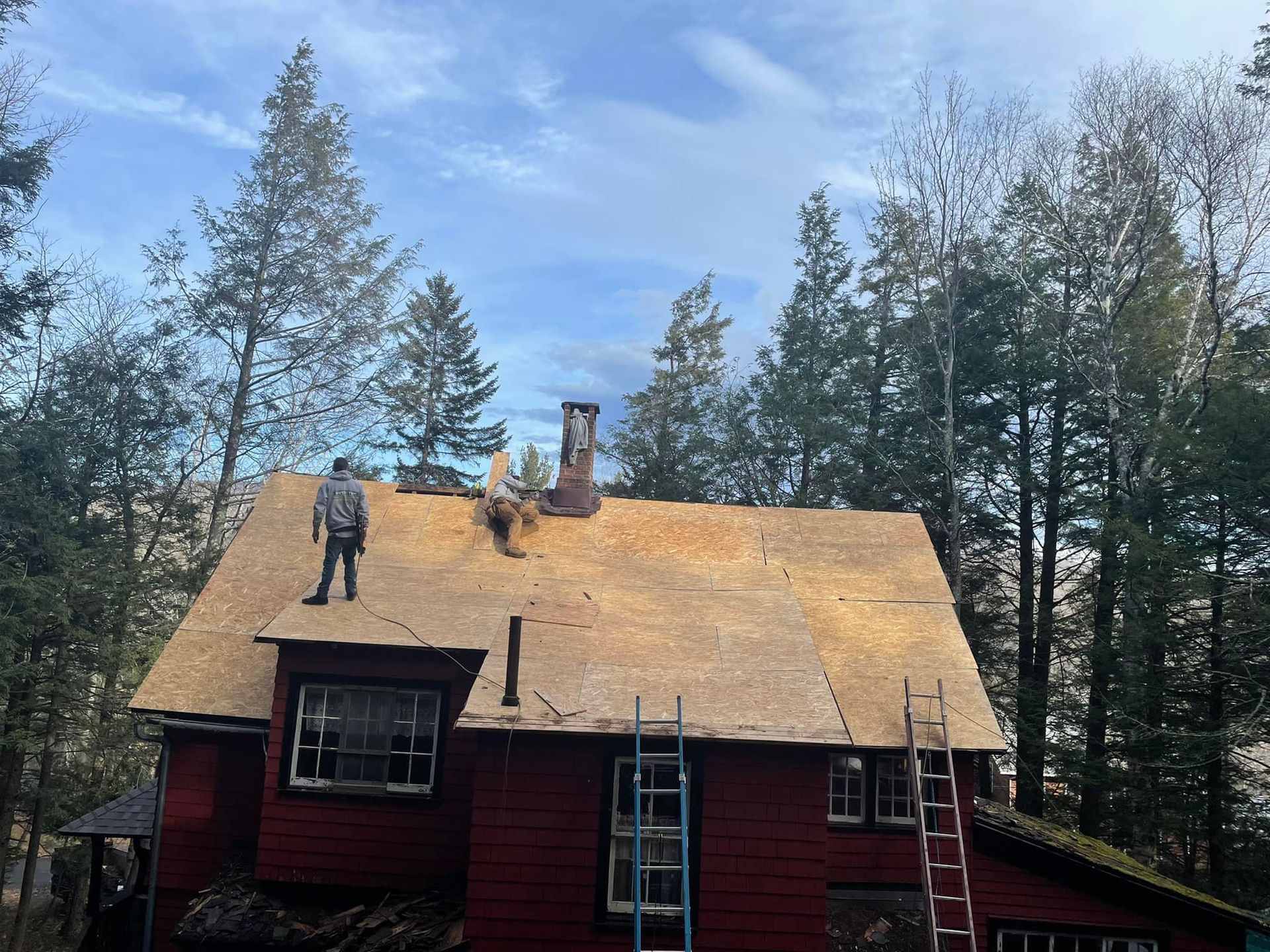 A man is standing on the roof of a red house.