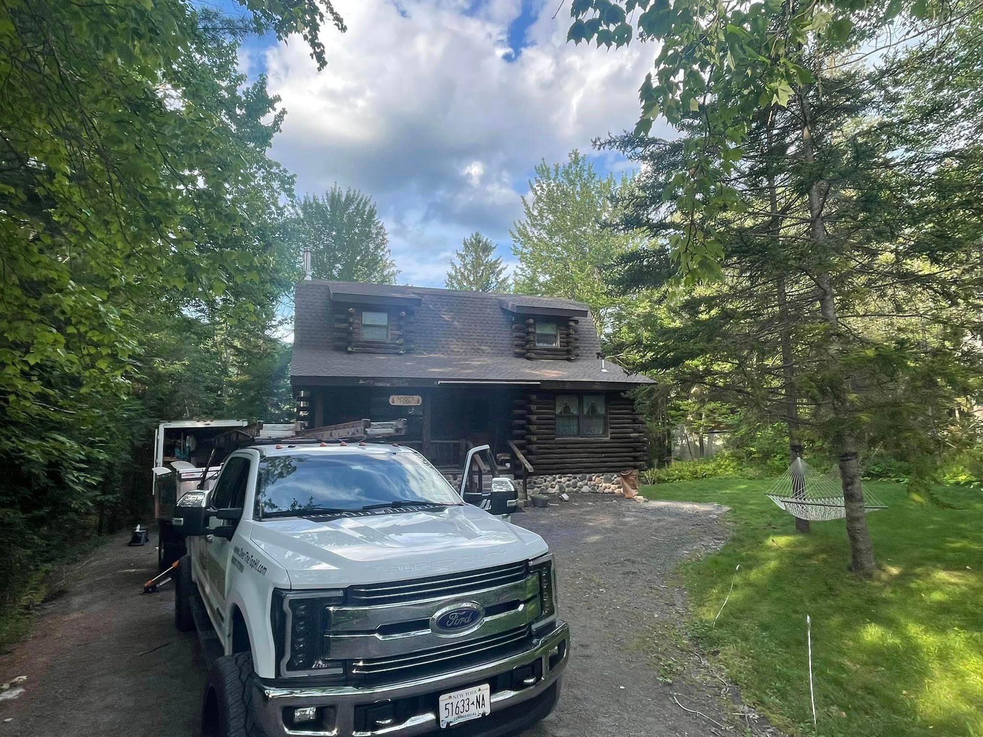 A white truck is parked in front of a log cabin.