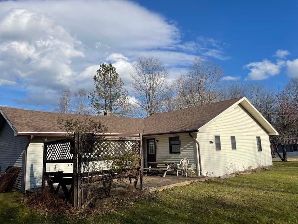 A white house with a brown roof and a porch