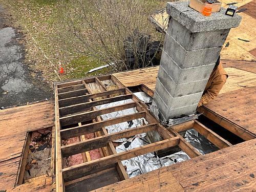 A chimney is being removed from the roof of a house.