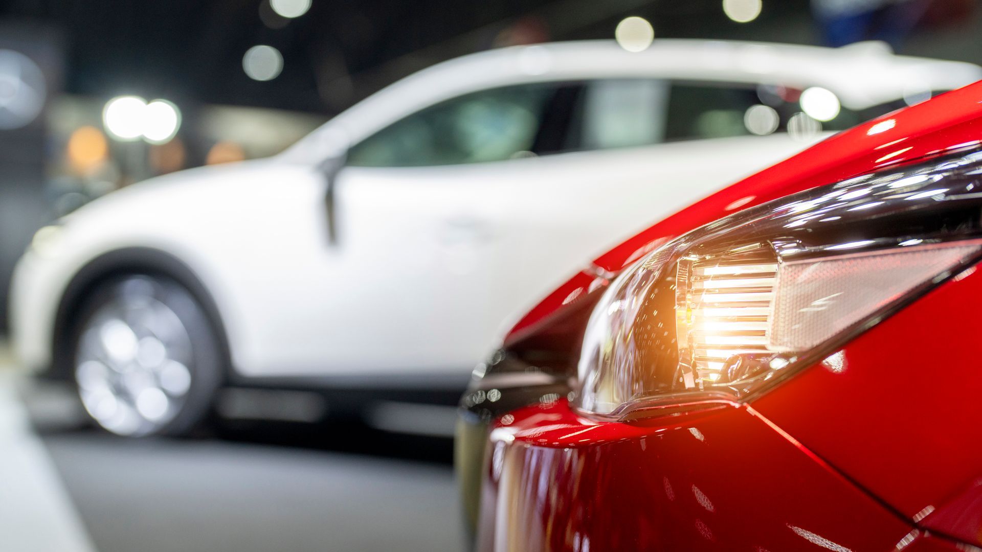 A red car is parked next to a white car at a car show.
