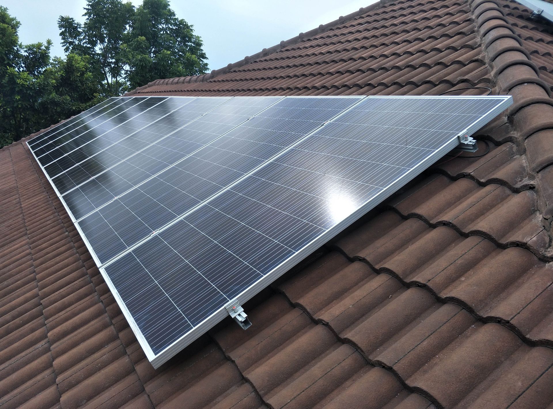 A row of solar panels sitting on top of a tiled roof