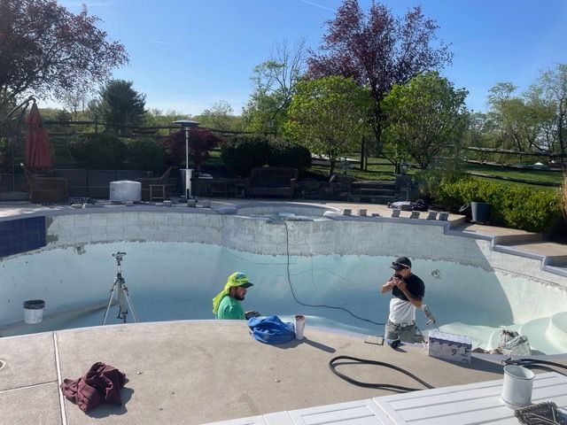Empty swimming pool with steps, concrete border, and light-colored interior. Sunny outdoor setting.
