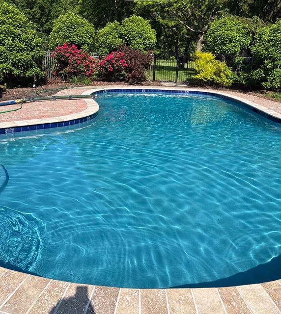Round blue tiled pool with water, bordered by red brick.