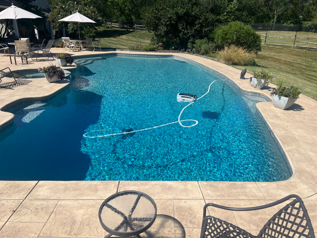 Round blue tiled pool with water, bordered by red brick.