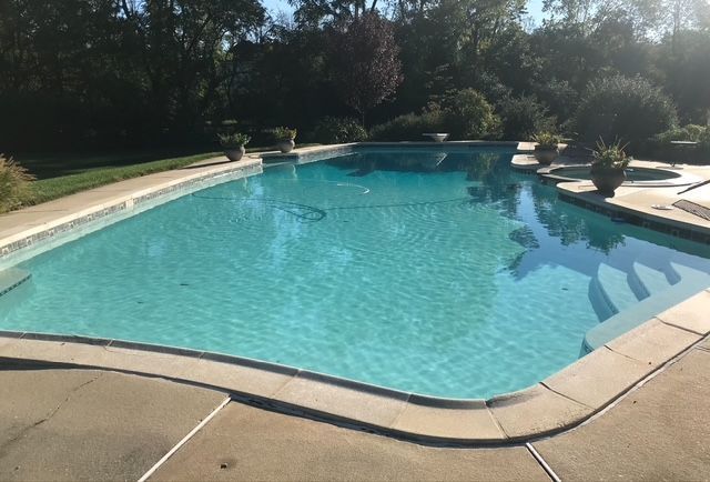 Pool tiles with water cascading over them. Blue and white tiles with diamond pattern at the top, light blue water.