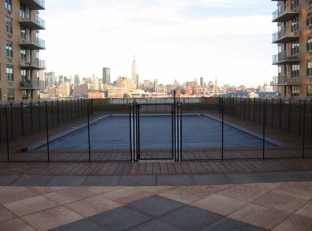 Mesh black child pool safety fence installed into concrete deck and stone retaining wall