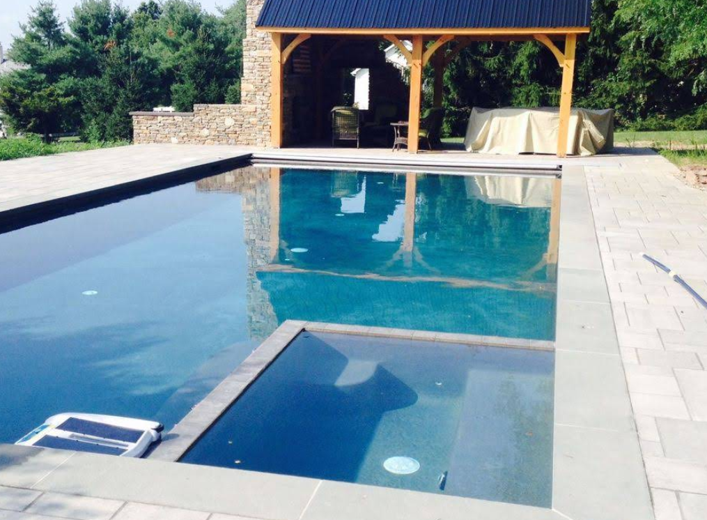 Swimming pool with attached jacuzzi, patio area with a gazebo.