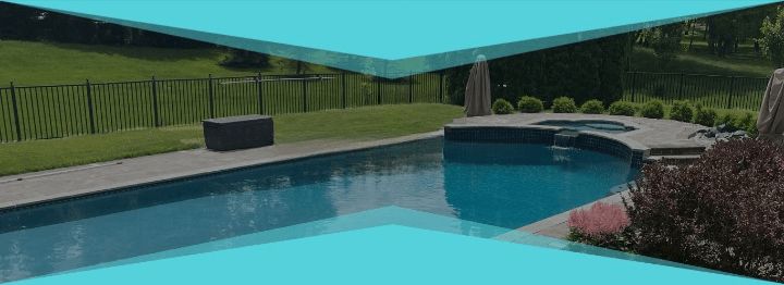 A rectangular pool with clear blue water, surrounded by greenery.