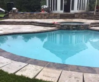 Pool with gazebo reflection.  Stone patio with hot tub. Green grass.