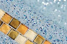 Pool with waterfall feature, stone walls, and lush greenery in a backyard setting.