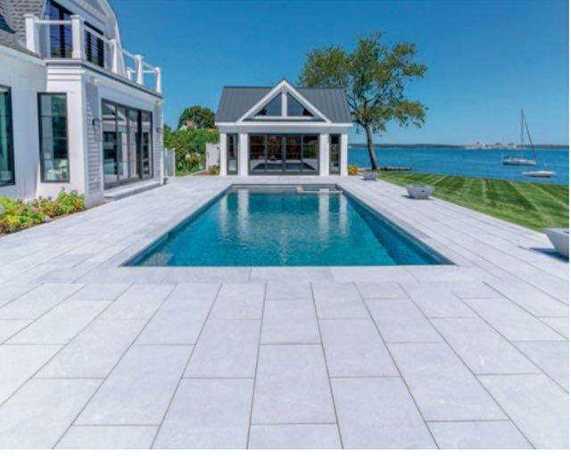 Pool with a dark blue interior, surrounded by light concrete patio.