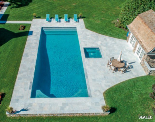 Pool with a dark blue interior, surrounded by light concrete patio.