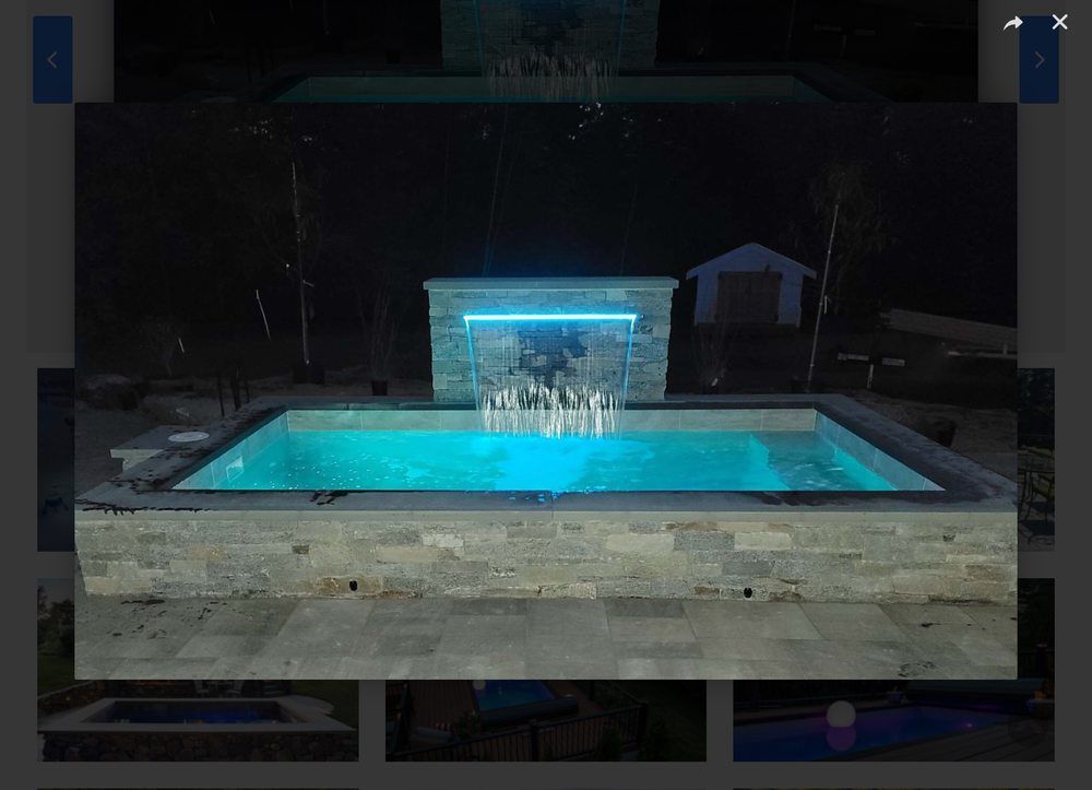 Pool with a dark blue interior, surrounded by light concrete patio.