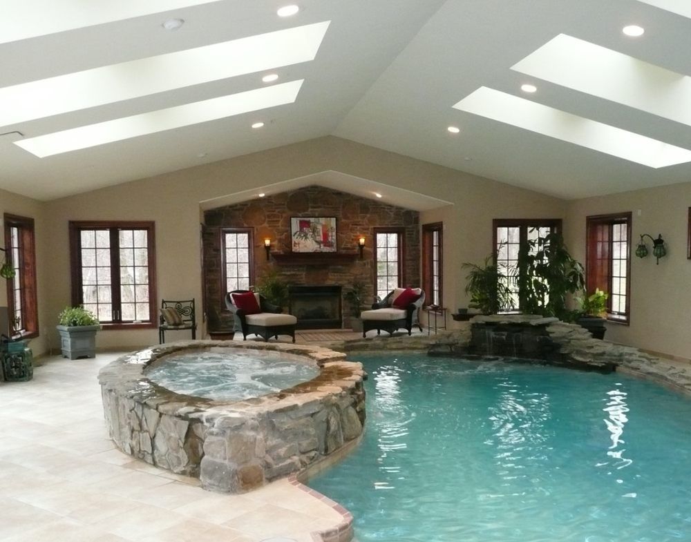 Indoor pool and jacuzzi with stone accents, fireplace, and skylights.