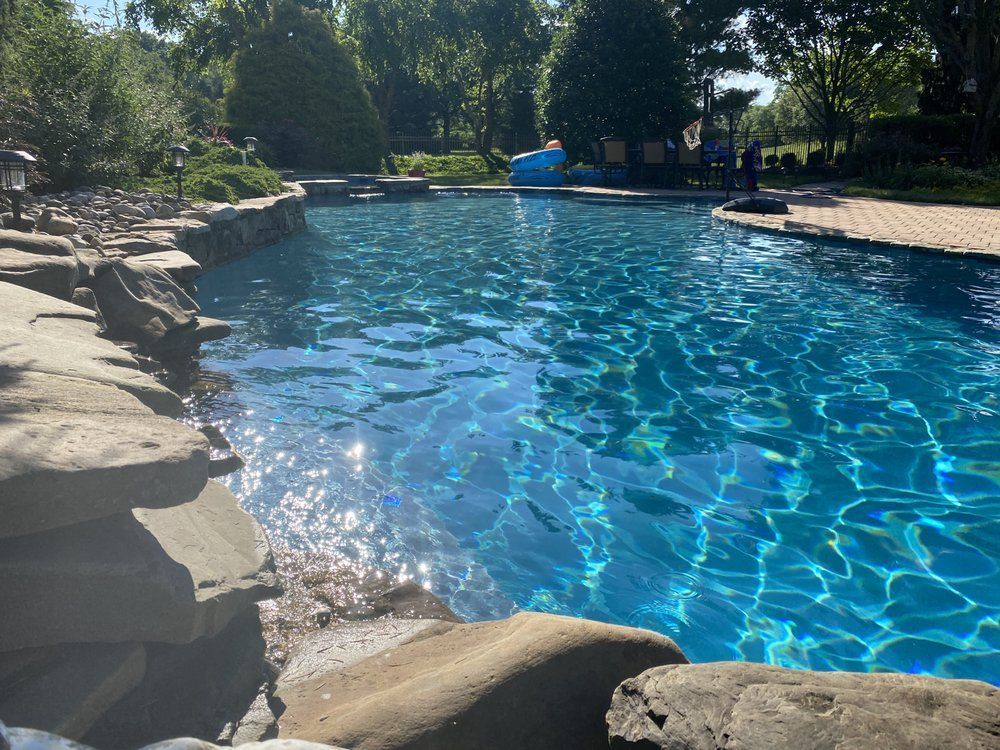 Swimming pool with blue water and stone edging on a sunny day.