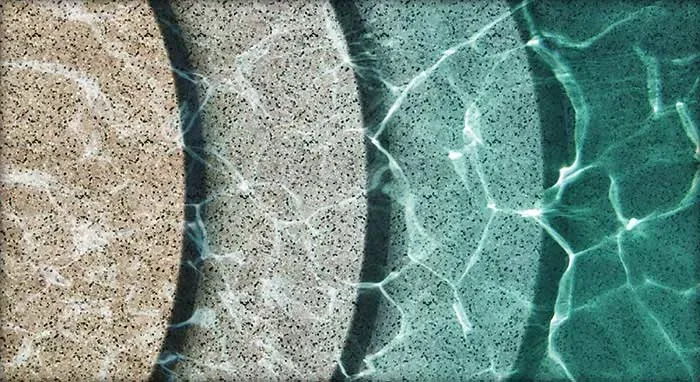 Pool with a dark blue interior, surrounded by light concrete patio.