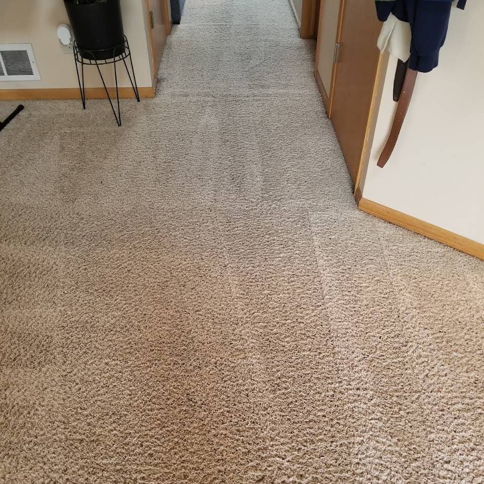 A person is standing on a carpeted floor in a hallway.