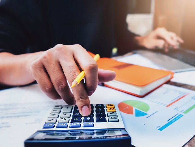 Žmogus naudoja skaičiuotuvą su rašikliu rankoje.