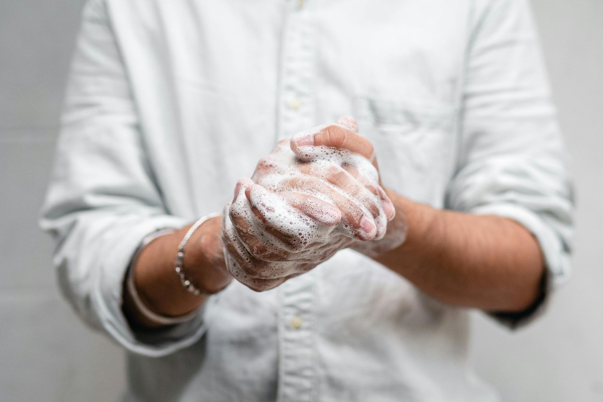 Person in light shirt washing hands with foamy soap.