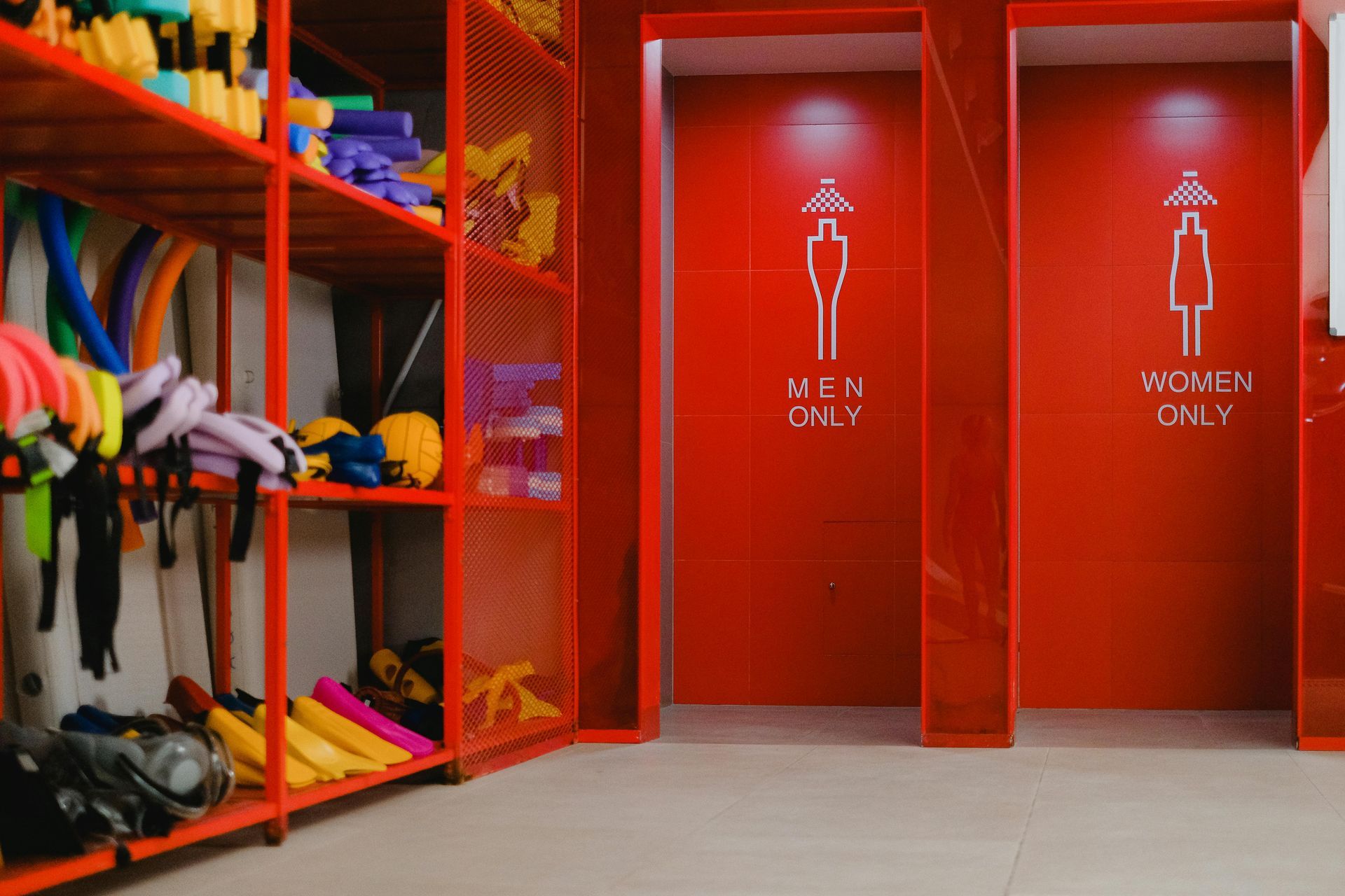 Red locker room with storage shelves and restrooms with gendered icons.
