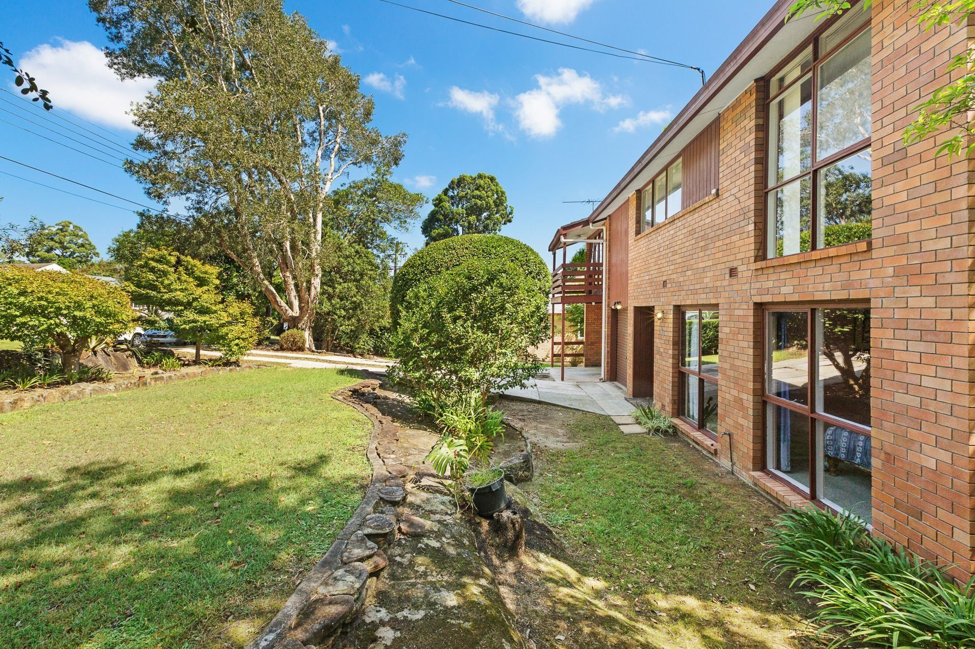 A large brick building with a lot of windows is surrounded by trees and grass.