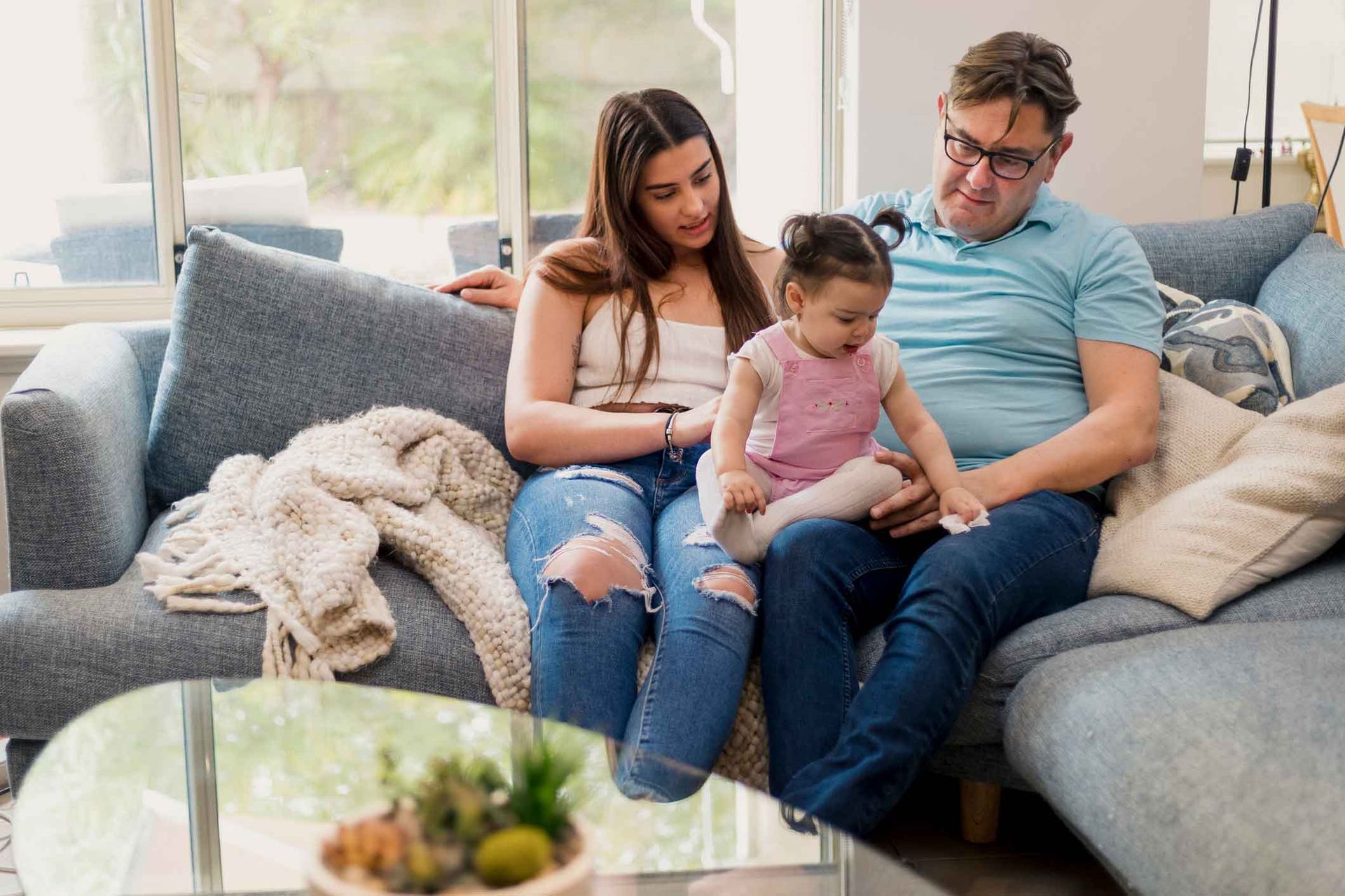 A man and woman are sitting on a couch with a little girl.