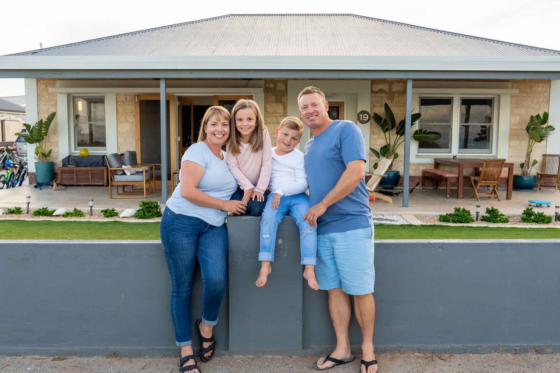 A family is posing for a picture in front of their house.