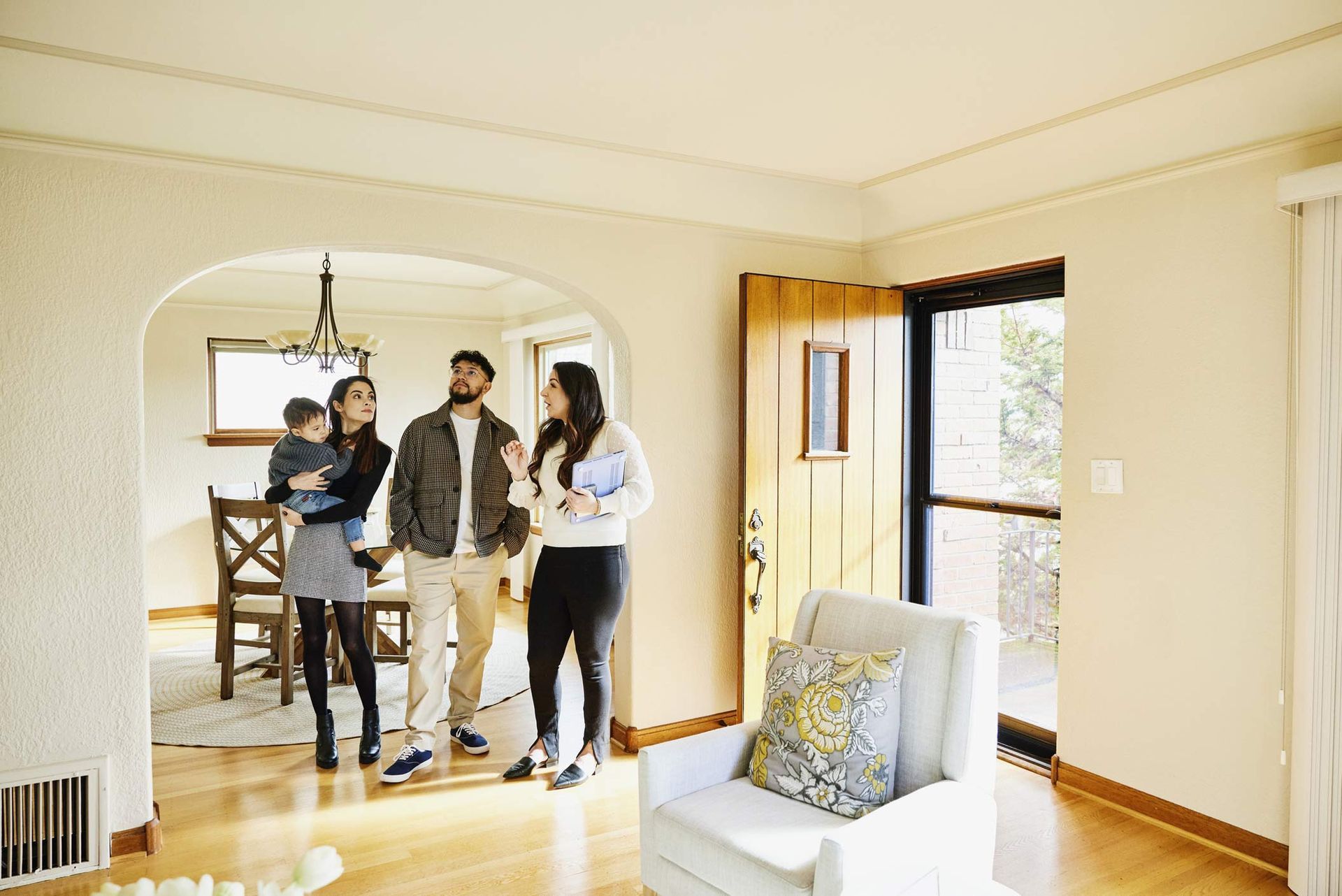 Family touring modern home with hardwood floors and open archway