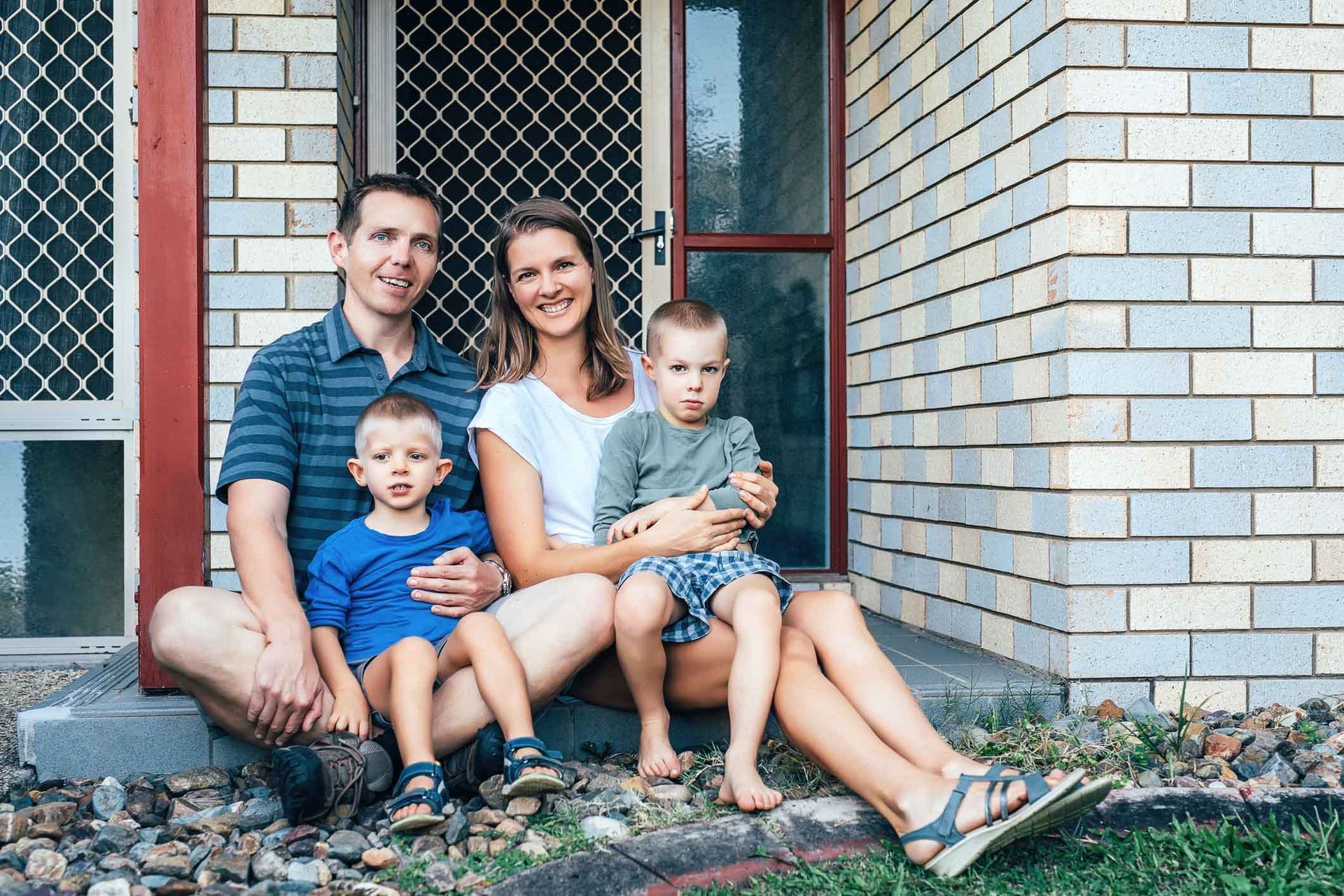 A family is sitting on the porch of their house.