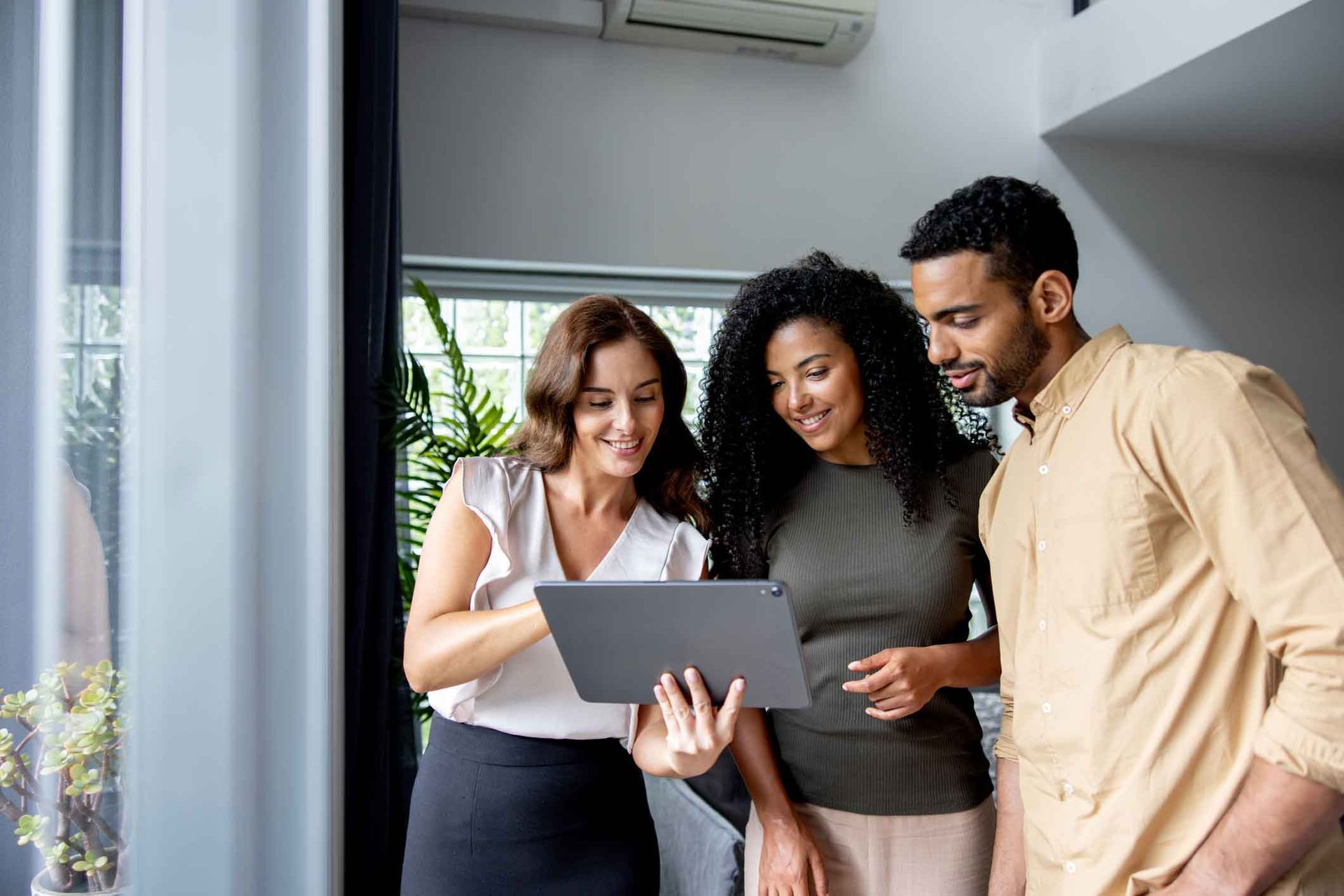 A man and two women are looking at a tablet together.