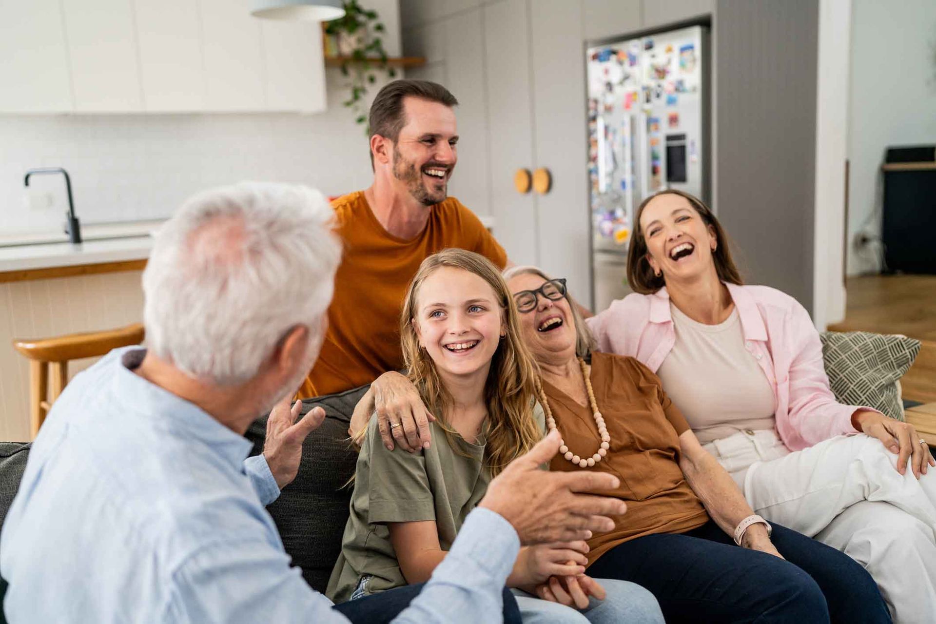 A family is sitting on a couch laughing together.