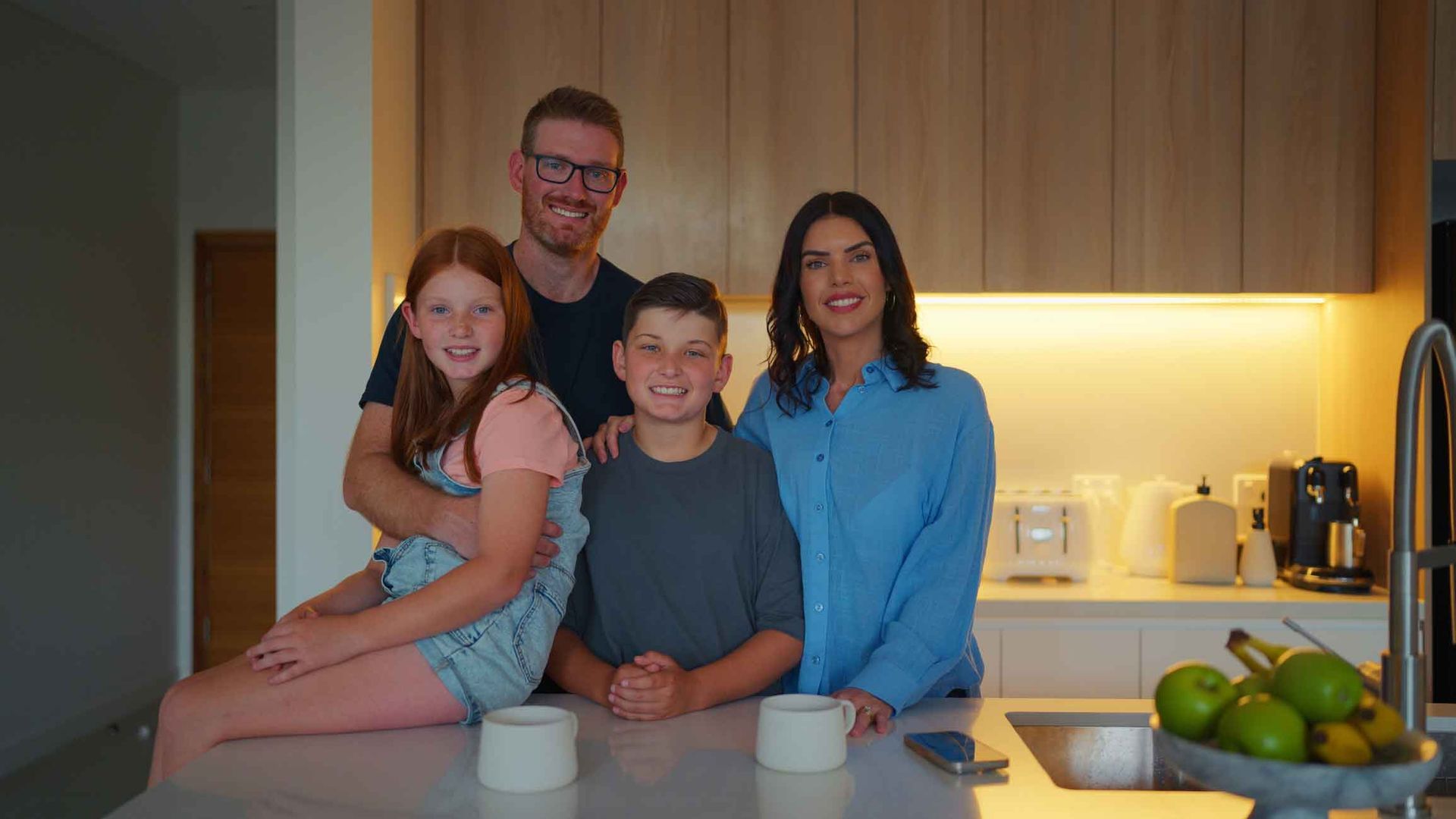 A family is posing for a picture in the kitchen.