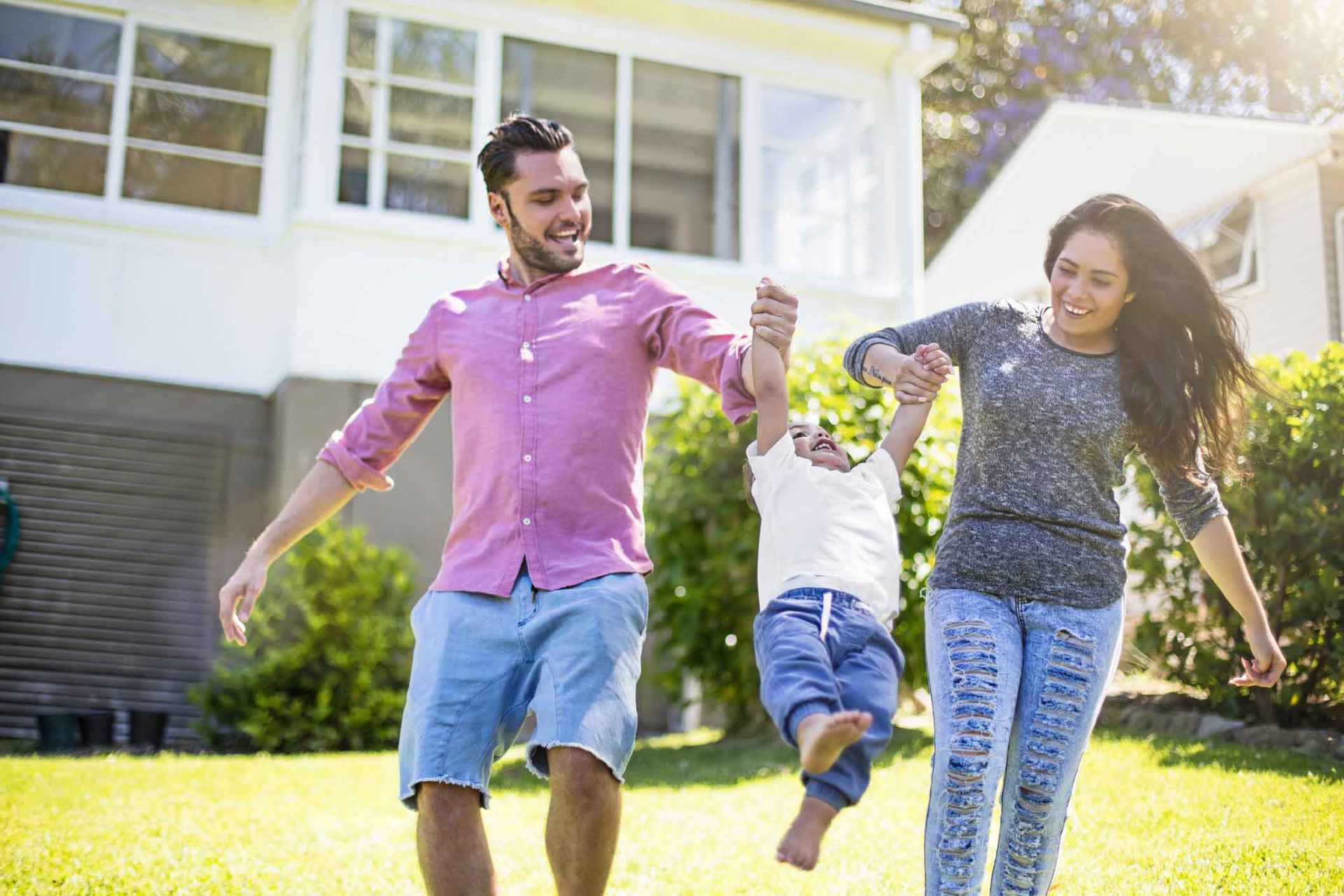 A family is walking in front of their house holding hands.