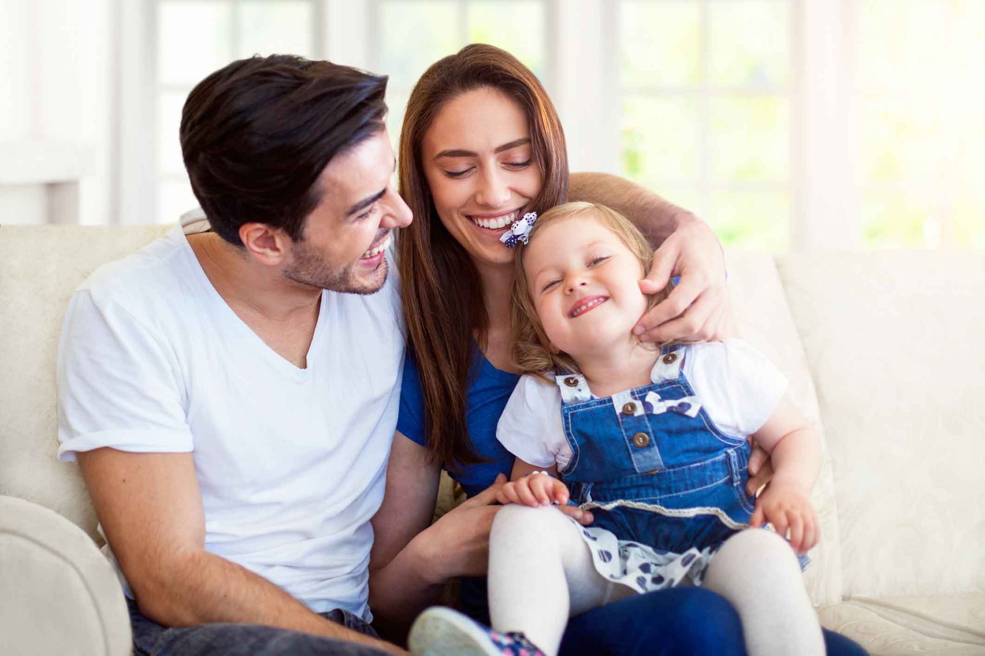 A man and woman are sitting on a couch with a little girl.