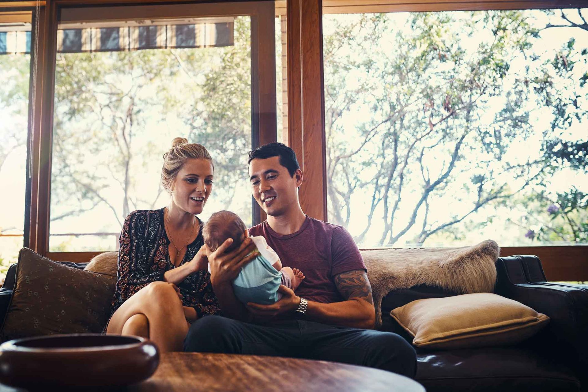 A man and woman are sitting on a couch holding a baby.