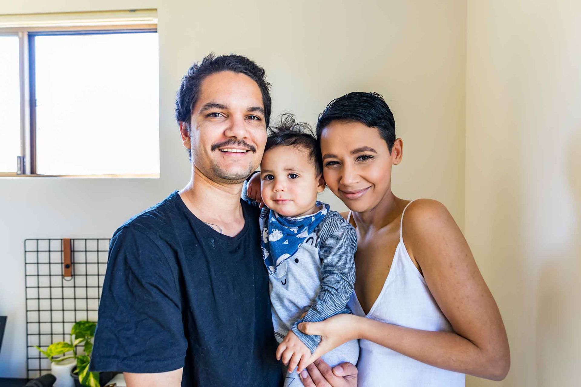 A man and a woman are holding a baby and posing for a picture.