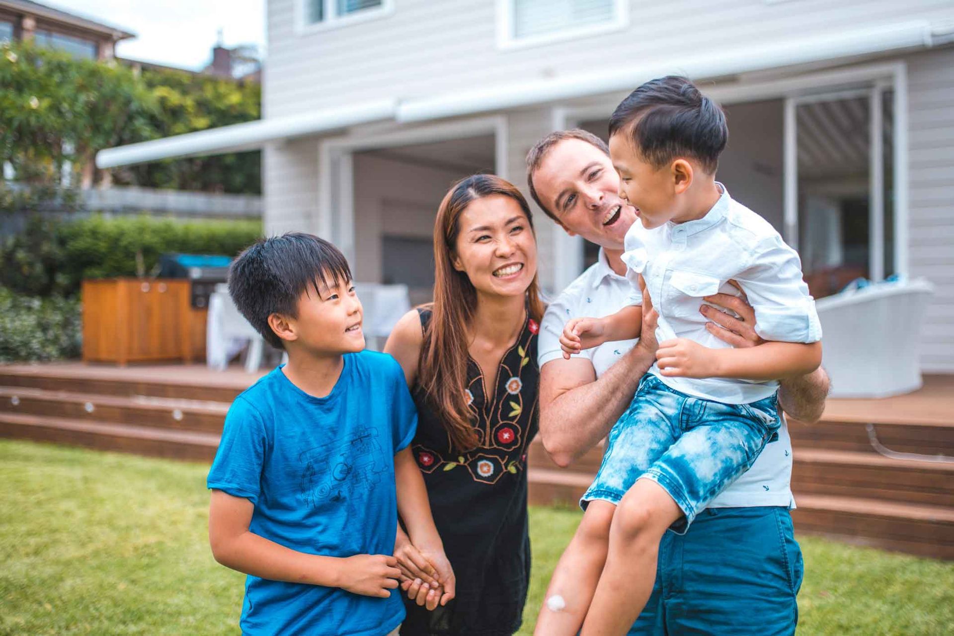 A family is posing for a picture in front of their house.