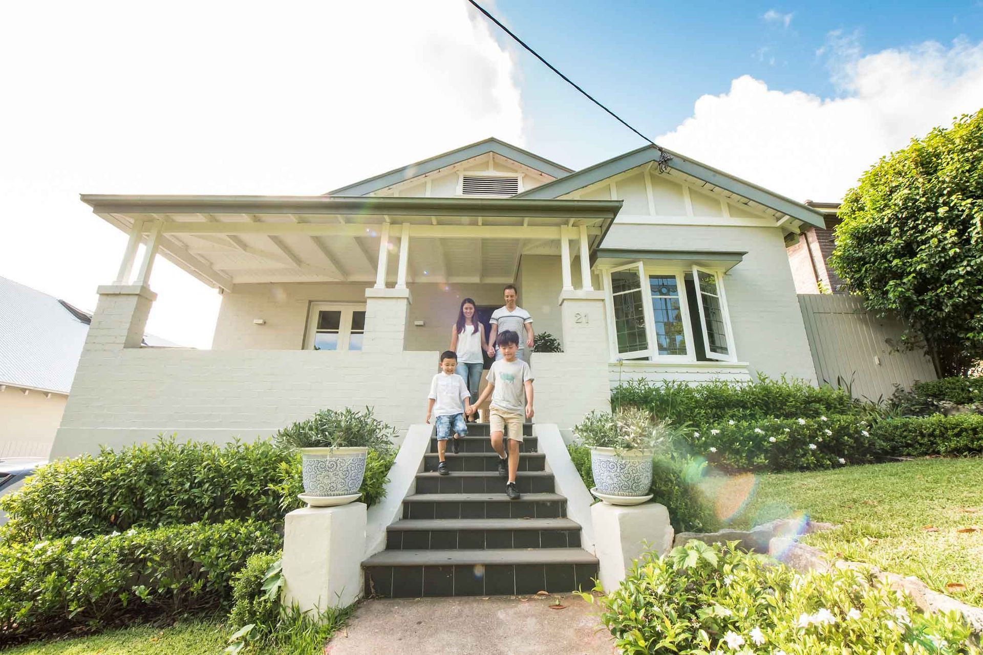 A family is walking up the stairs of a white house.