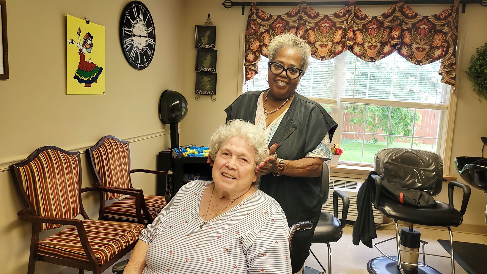 Caregiver assisting a resident in a common area at Newburgh Health and Rehab