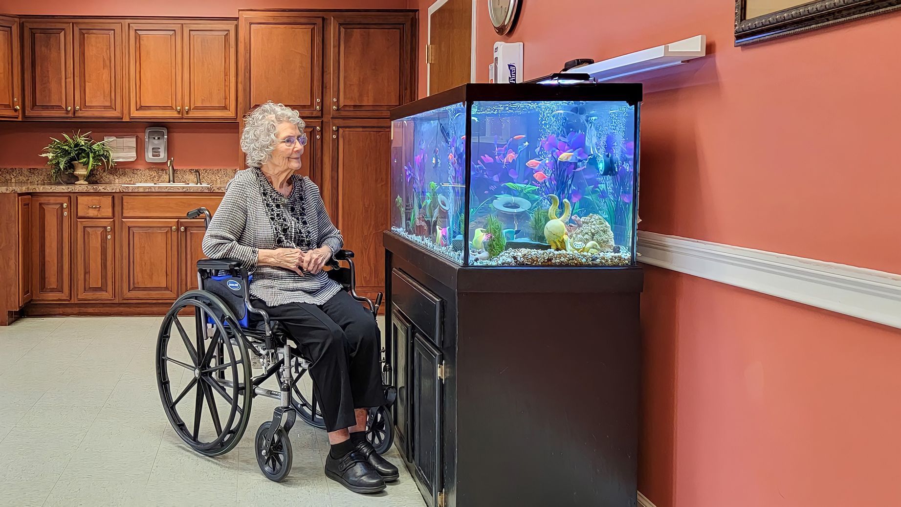 Resident seated near an aquarium at Newburgh Health and Rehab