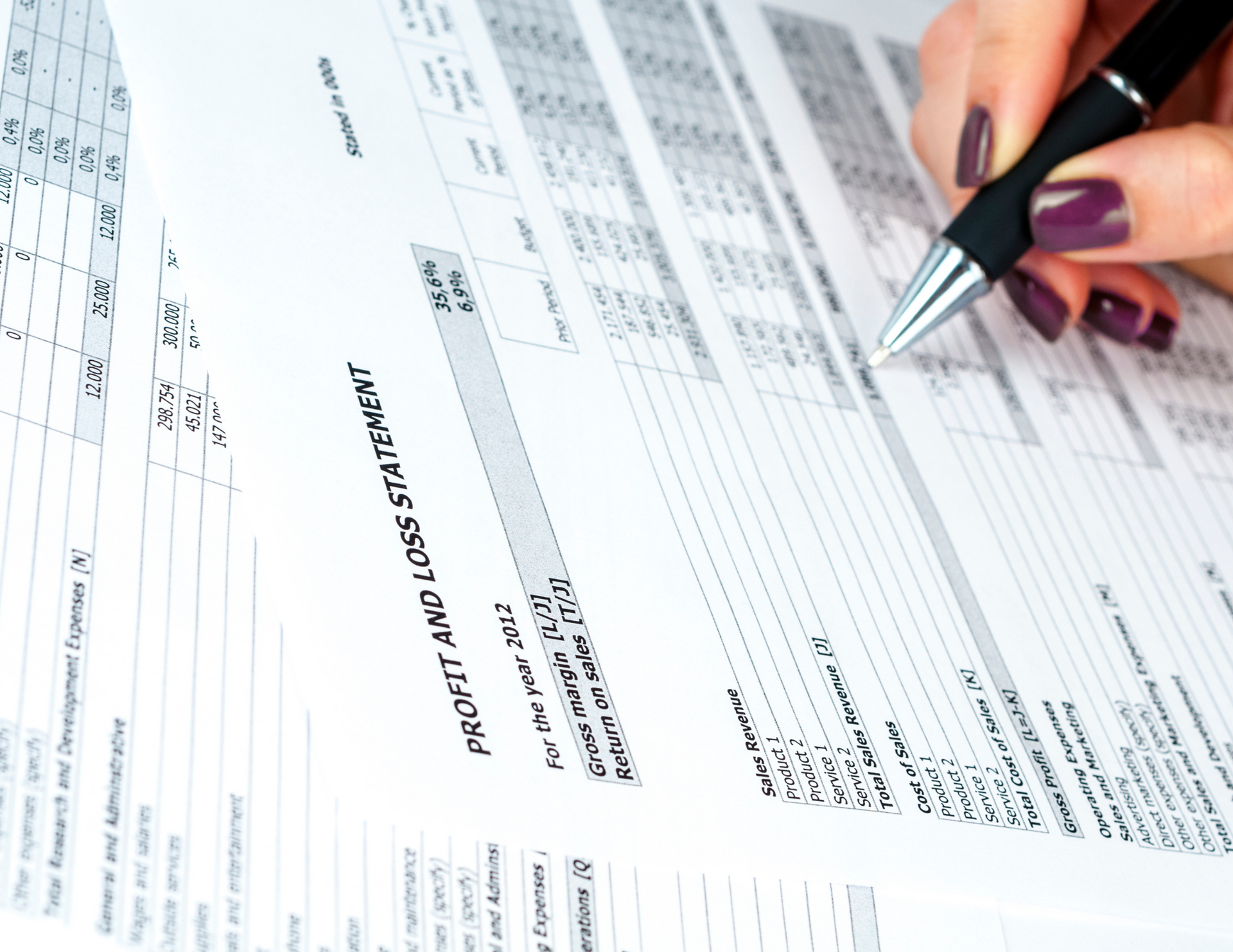 A person is writing on a profit and loss statement