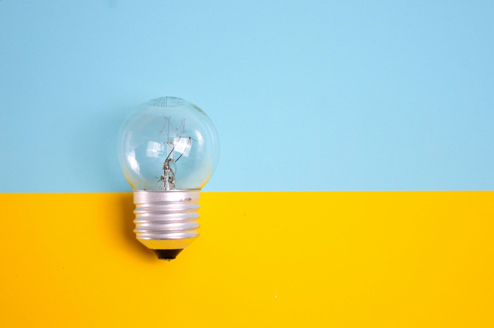 A light bulb is sitting on a blue and yellow background.