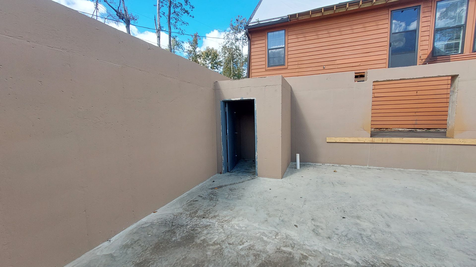 A brick building is being built next to a concrete wall.