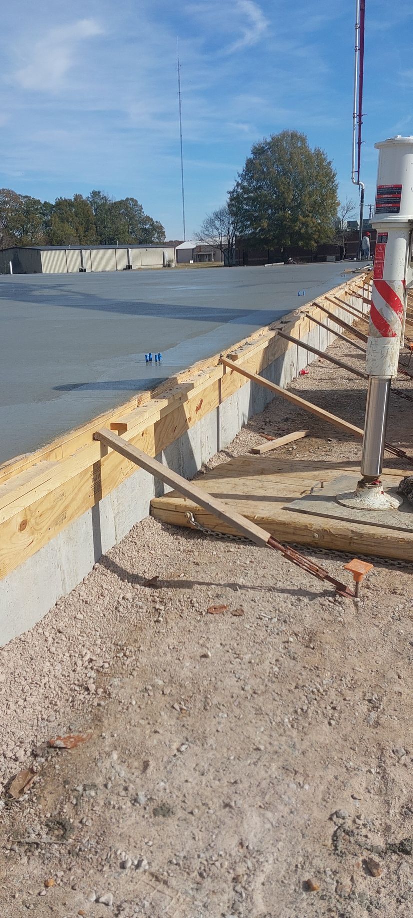 A construction site with a crane and a concrete foundation being poured.