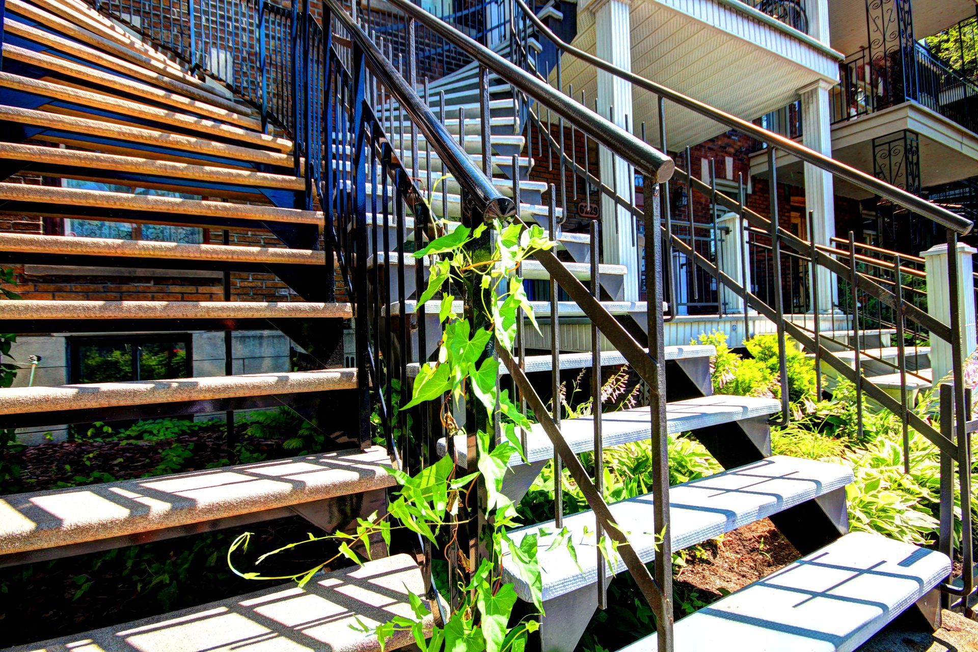 Un escalier menant à une maison avec une balustrade en métal.