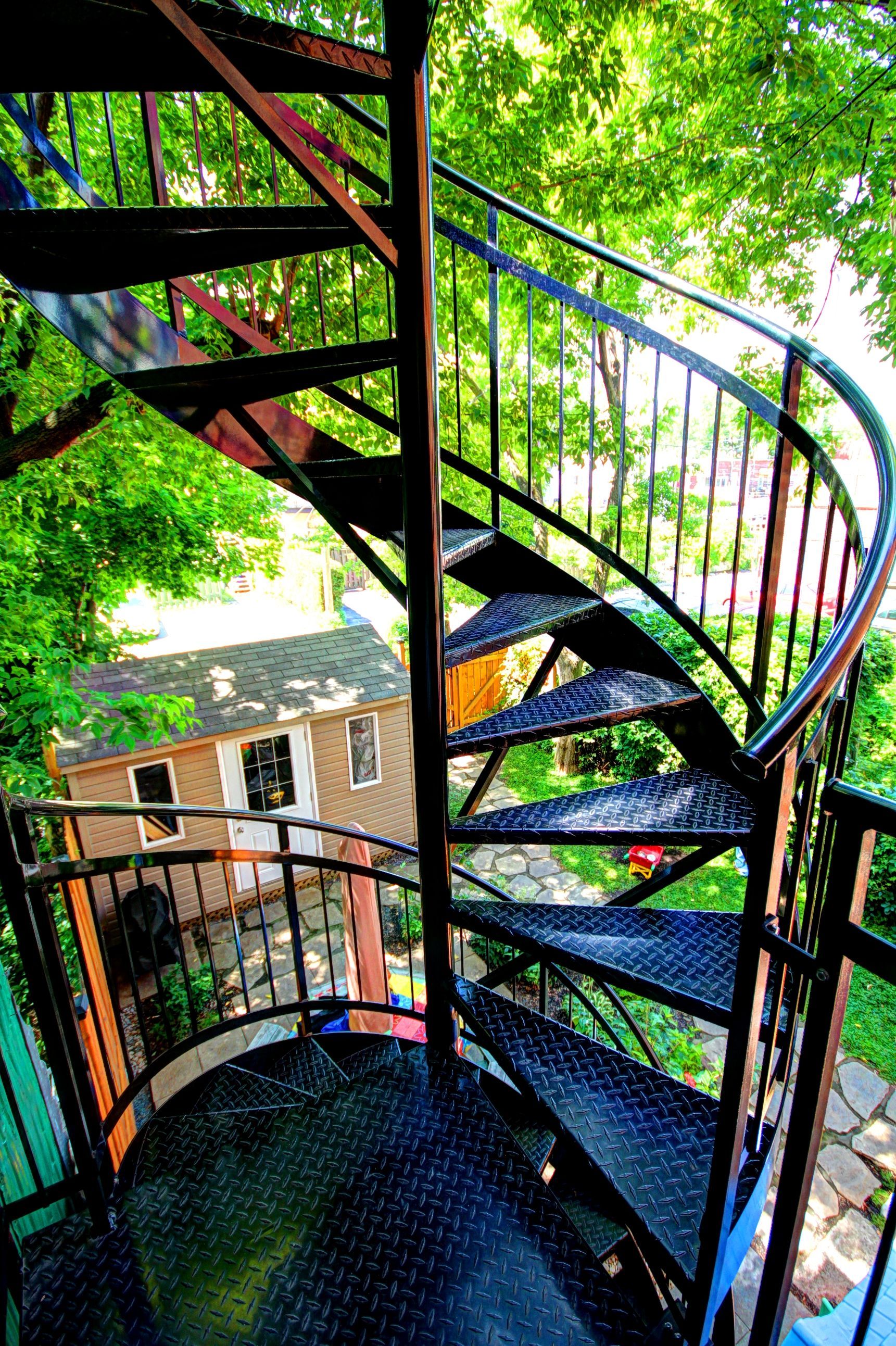 Un escalier en colimaçon menant à une maison entourée d'arbres.
