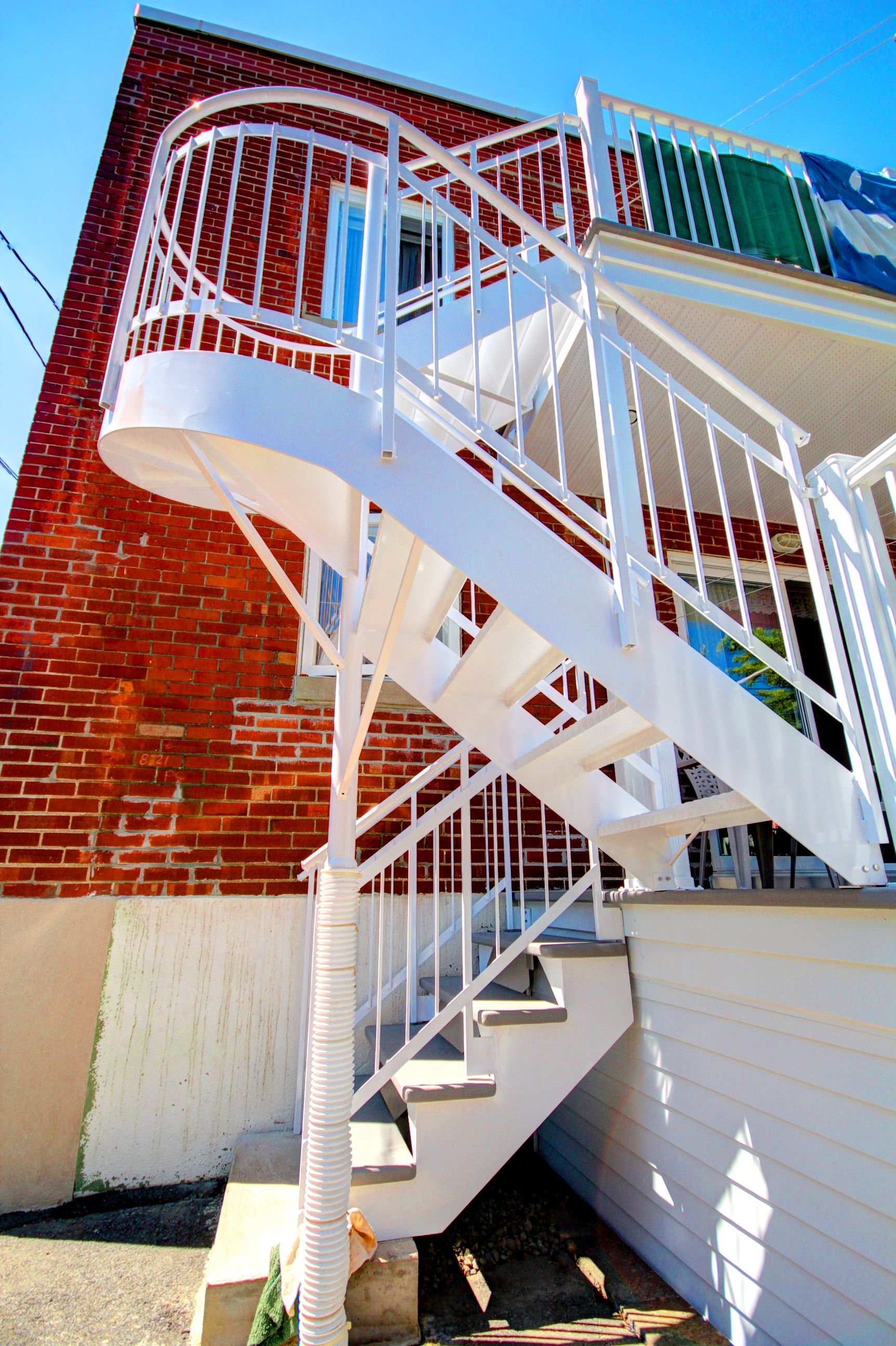 Un escalier en colimaçon blanc menant à un bâtiment en brique