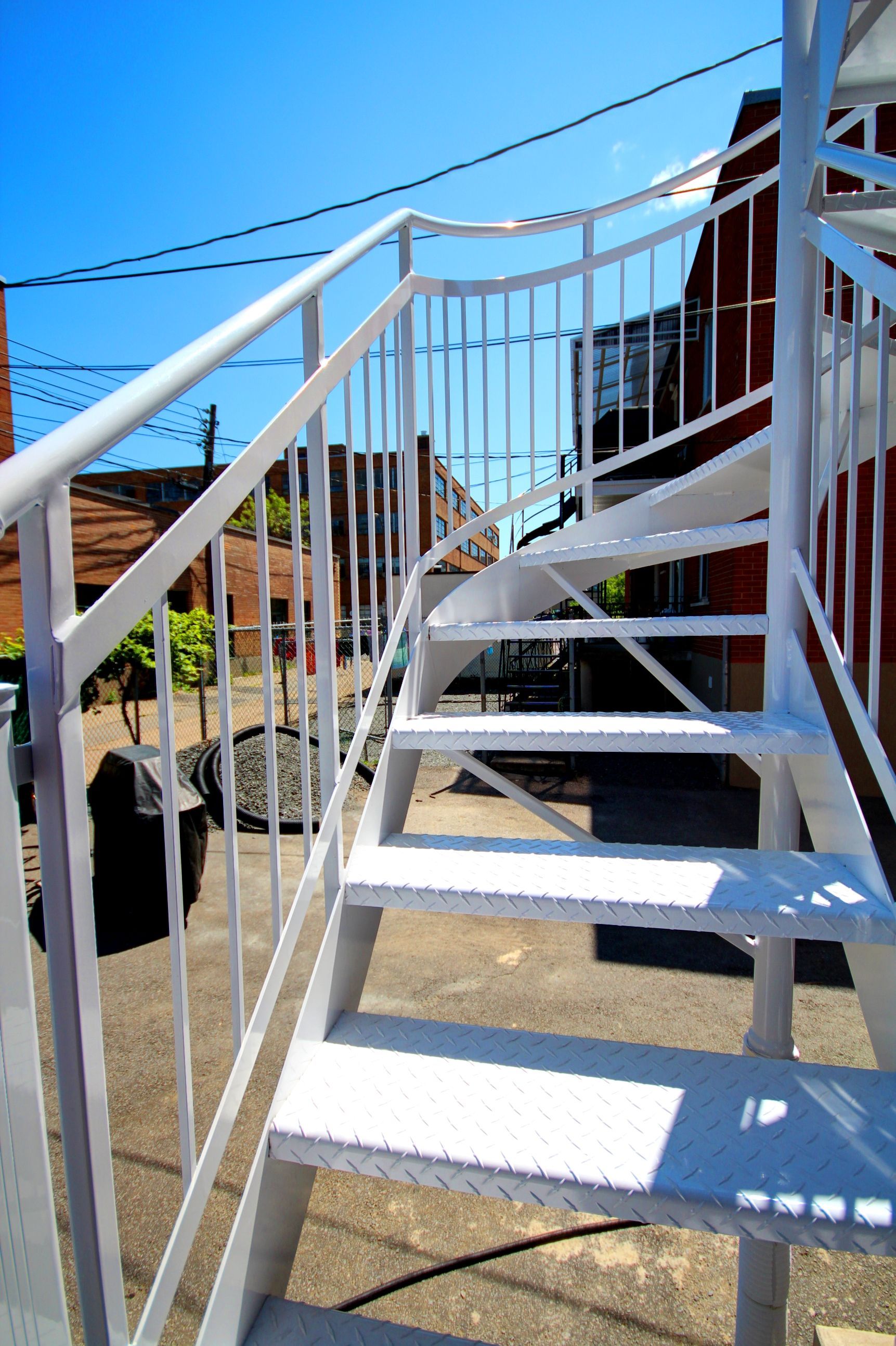 Un escalier en colimaçon blanc avec une balustrade blanche menant à un bâtiment