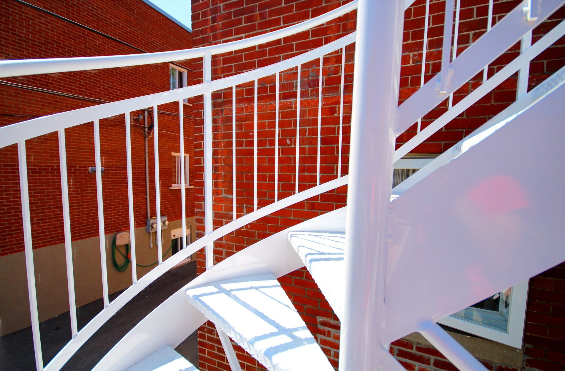 Un escalier en colimaçon blanc devant un bâtiment en brique rouge